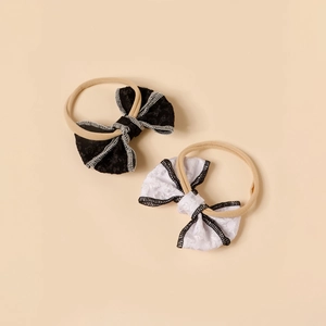 Detailed view of two-piece infant bow headbands in black and white jacquard lace fabric