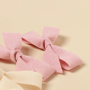 Close-up of handmade fabric bow hair clips showing knitted texture in pink and beige