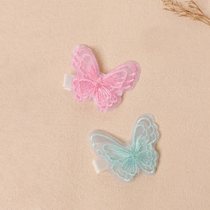 Dettaglio dei fermagli per capelli a farfalla in organza ricamata rosa e verde menta