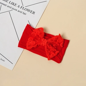 Dettaglio di una fascia rossa per neonati con un elaborato fiocco in pizzo traforato