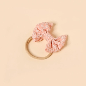 Detail of pink bow baby headband with white floral embroidery and nylon elastic band