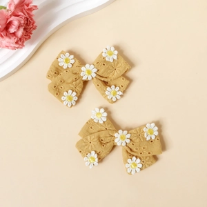 Vue détaillée de deux barrettes en coton jaune gingembre avec broderies de marguerites