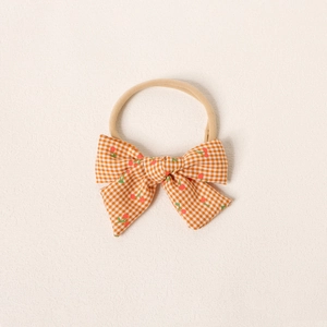 Détail du bandeau bébé avec nœud vichy orange et motifs cerises rouges sur nylon doux