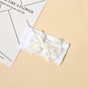 Dettaglio della fascia in pizzo bianco con ricamo floreale per neonati