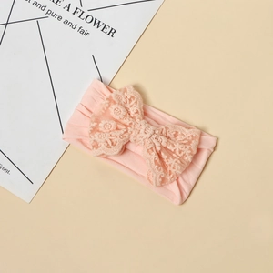 Dettaglio della fascia per neonata rosa in maglia con fiocco in pizzo e ricamo floreale