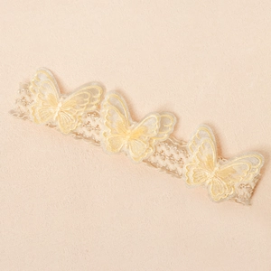 Detail eines Baby-Spitzenstirnbands mit drei lagigen 3D-Stickschmetterlingen und Pailletten