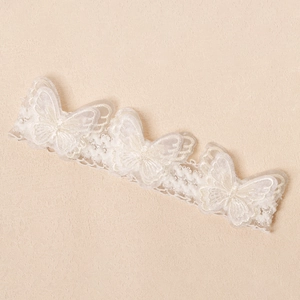 Detail eines weißen Spitzen-Stirnbands mit 3D-Schmetterlingen und Perlen für Babys