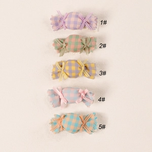 Close-up of five colorful candy-shaped fabric hair clips for kids in macalon plaid patterns