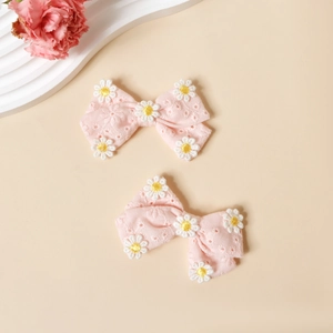 Détail de barrettes à nœud rose brodées avec motifs de marguerites pour enfants