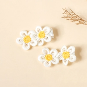 Detailed macro view of daisy flower hair clips with embroidered lace texture and ribbons