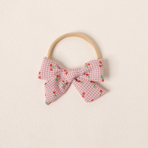 Gros plan du bandeau bébé en nylon avec un nœud aux motifs vichy cerise rose