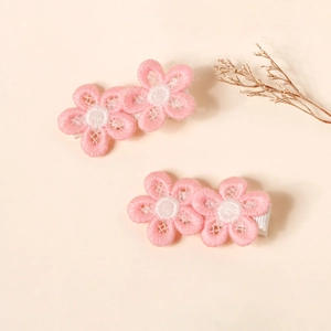 Close-up of pink embroidered flower hair clips for babies with soft ribbon wrapping