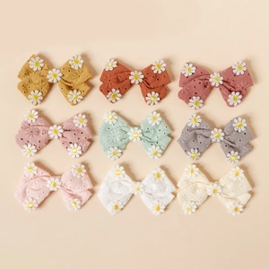 Vue à plat de neuf pinces à cheveux en coton coloré avec broderie de marguerites blanches
