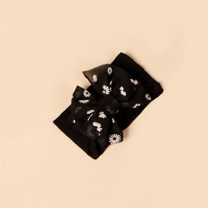 Detail of soft nylon baby headband featuring a black floral bow with daisy prints