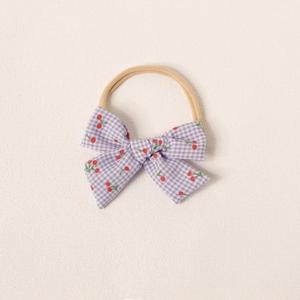 Détail d'un bandeau bébé avec nœud à carreaux lilas et cerises sur nylon souple