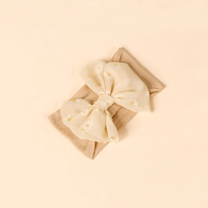Detail of baby headband featuring a light yellow chiffon bow with white daisy print