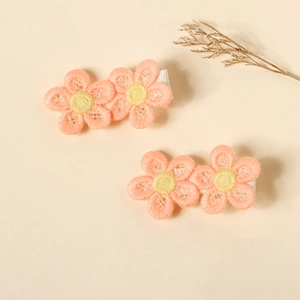 Close-up of embroidered pink flower hair clips with soft fabric lining for baby girls