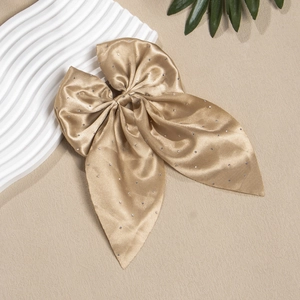Détail d'un nœud papillon en satin champagne avec strass brillants sur fond de pierre