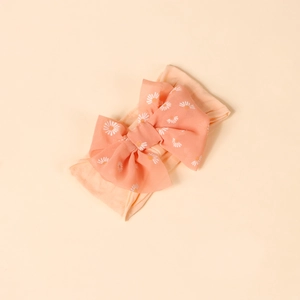Detail of coral orange bow headband with white daisy print on soft elastic nylon fabric