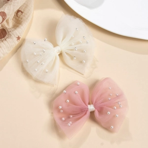 Gros plan de barrettes nœuds en tulle avec perles artificielles roses et crème