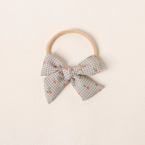 Détail du bandeau bébé avec nœud à carreaux gris et motif cerise rouge sur nylon