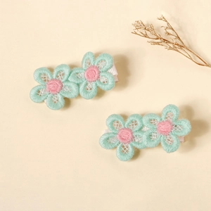 Close-up of two handmade mint green floral hair clips with pink centers and fabric wrap