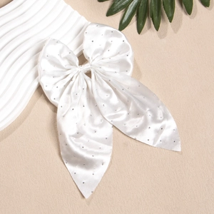 Détail d'un grand nœud en satin blanc avec strass argentés pour cheveux sur fond clair