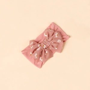 Close-up of soft pink nylon baby headband with a large white daisy floral bow