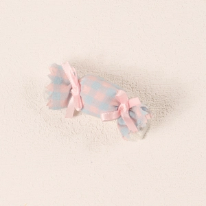Detail of candy-shaped hair clip with pink and blue checkered fabric and satin bows