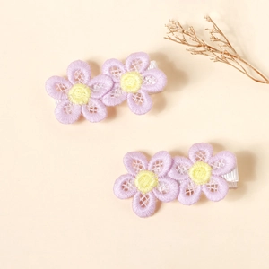 Detailed view of two handmade floral embroidered hair clips with soft fabric lining