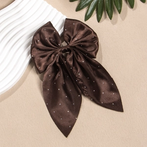 Détail de la barrette à cheveux nœud en satin marron foncé avec strass scintillants