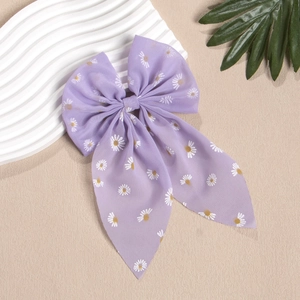 Detailansicht einer lila Chiffon-Haarschleife mit weißem Gänseblümchen-Muster