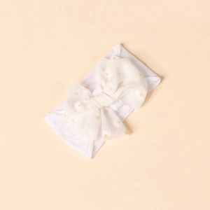 Macro detail of soft nylon baby headband featuring a white daisy print chiffon bow