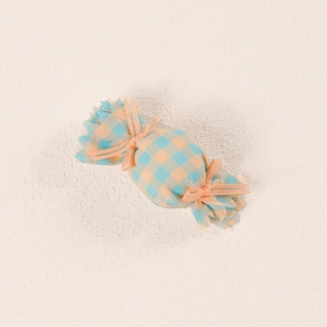 Detailed view of candy-shaped hair clip featuring blue and orange plaid fabric textures
