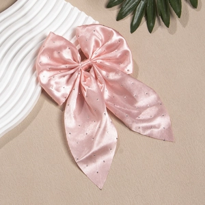Gros plan du nœud en satin rose avec strass brillants sur un support décoratif élégant