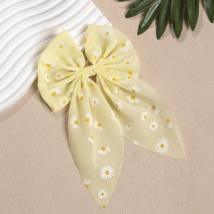 Detail der gelben Haarklammer mit Gänseblümchen-Print und langen Chiffon-Bändern
