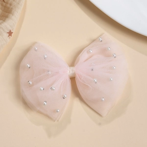 Vue détaillée d'une barrette nœud en tulle rose avec perles nacrées et pince en tissu