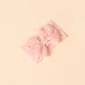 Close-up of pink baby headband featuring white daisy prints and a large bow design