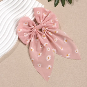 Details einer Haarklammer mit rosa Gänseblümchen-Druck und fließenden Bändern