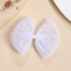 Détail de la pince à cheveux avec nœud en maille blanche orné de perles et tissu doux