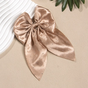 Détail du nœud papillon en satin champagne avec strass scintillants et longs rubans soyeux