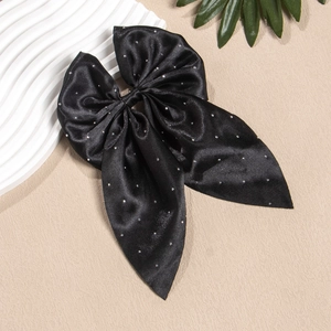 Détail d'un nœud papillon en satin noir avec strass brillants et longs rubans pour cheveux