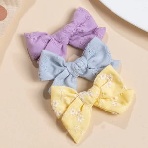 Detailed view of handmade embroidered cotton bow hair clips in pastel floral patterns