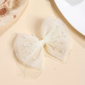 Détail d'une pince à cheveux en tulle blanc crème avec perles sur fond en tissu