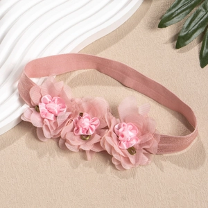 Detail eines rosa Baby-Haarbandes mit drei handgefertigten Blumen aus Tüll und Satin