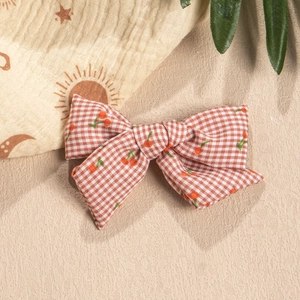 Detailed view of red and white plaid bow hair clip with cute cherry patterns