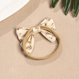 Floral print bow baby headband with elastic nylon band on a clean aesthetic background