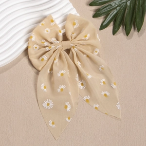 Detail der beigen Chiffon-Haarschleife mit Gänseblümchen-Print und langem weichem Band