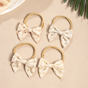 Flat lay of four floral cotton bow nylon headbands for babies in pastel colors