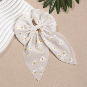 Makroaufnahme einer weißen Chiffon-Haarschleife mit gelben Gänseblümchen und Bändern